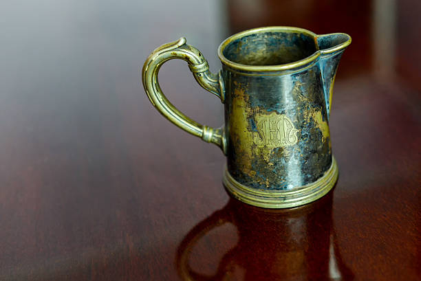 Old brass cup sitting on a glossy wood