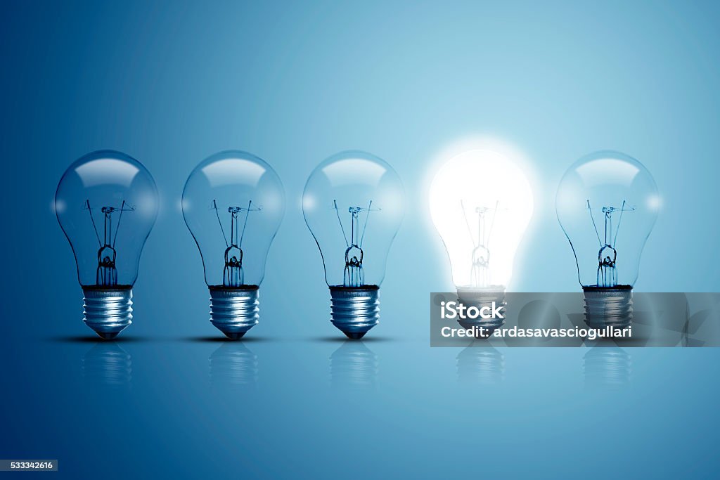 Five bulbs and one of them is glowing. Five bulbs on a blue background and one of them is glowing. Light Bulb Stock Photo