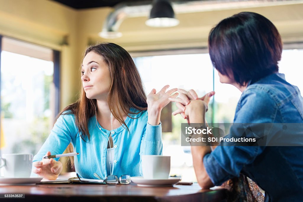 Annoyed teen girl talking to mother in coffee shop Rudeness Stock Photo