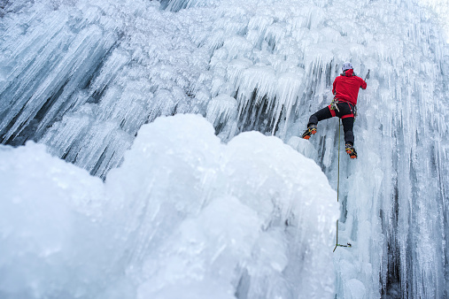 Ice climber ascending a frozen waterfall.