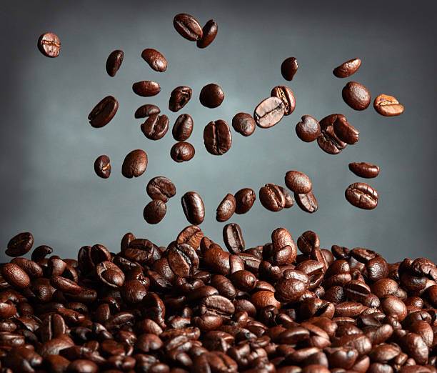 Flying coffee beans over dark background stock photo