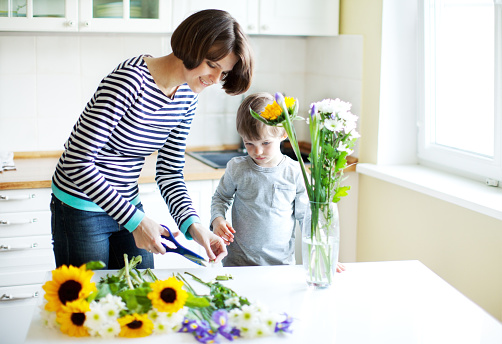 Mother and son putting flowers in vase