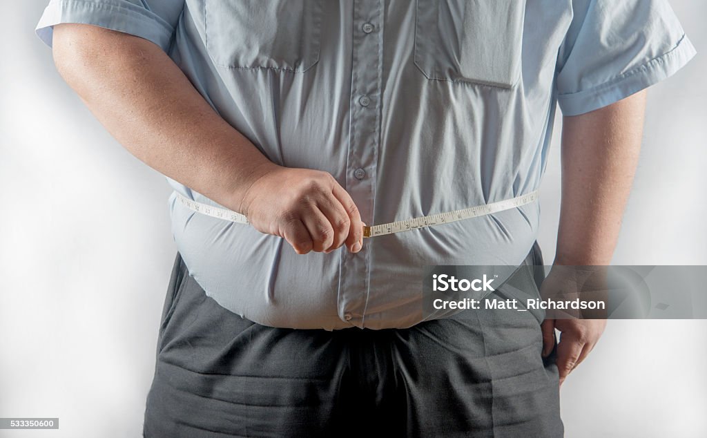 Obese man measuring his waist Obese man measuring his waist with a tape measure. UK Body Conscious Stock Photo