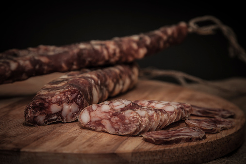 home-made salami on a wooden board. Shallow depth of field