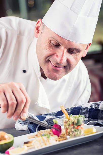 istock Chef in hotel or restaurant kitchen decorating dish with tweezers. 533351988