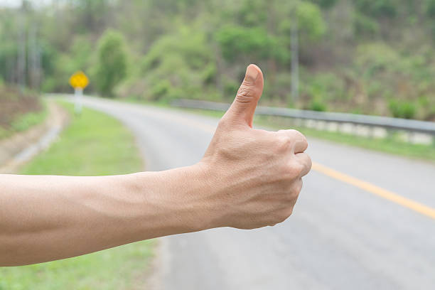 istock hand and hitchhiking sign on road 533352584