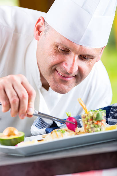 istock Chef in hotel or restaurant kitchen decorating dish with tweezers. 533353726