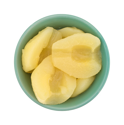 Top view of a bowl full of canned pear halves isolated on a white background.