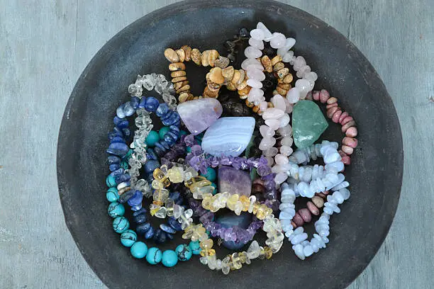 Healing properties of gemstones and crystals on a pottery bowl with wooden background