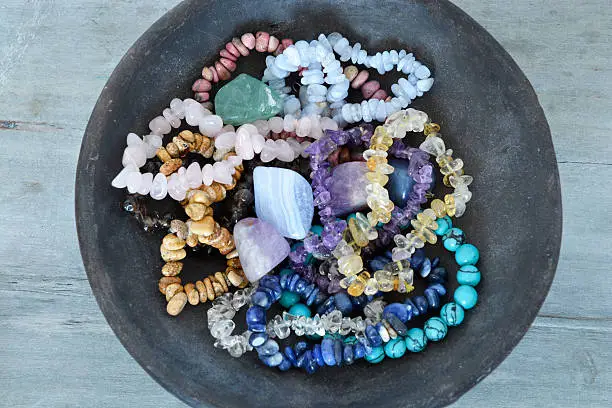 Healing properties of gemstones and crystals on a pottery bowl with wooden background