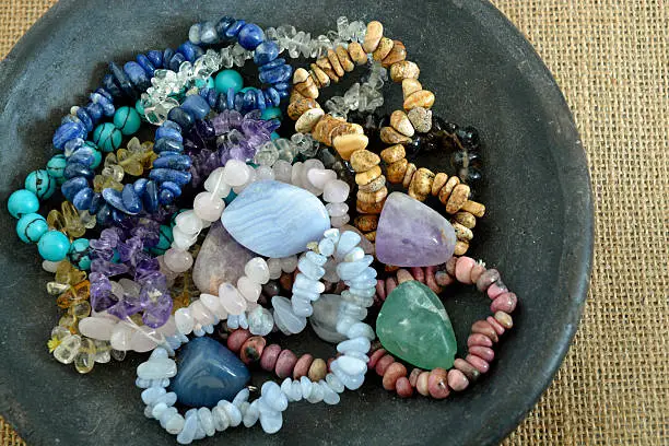 Healing properties of gemstones and crystals on a pottery bowl with jute background