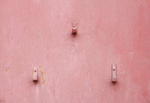 old pink metal sheet with three hooks, texture