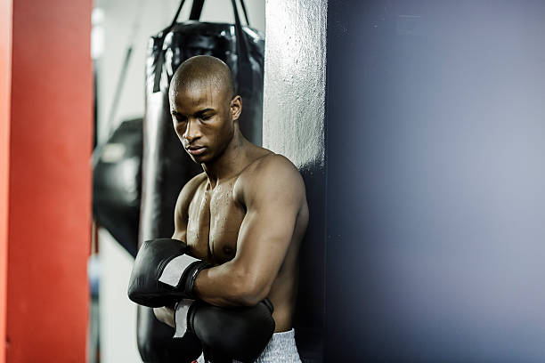 istock Tired shirtless boxer leaning on wall after training 533355380
