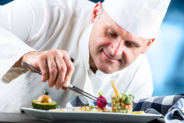 istock Chef in hotel or restaurant kitchen decorating dish with tweezers. 533355508