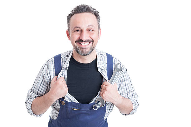 Cheerful attractive mechanic with metallic spanner acting like superman and tearing his shirt off isolated on white background
