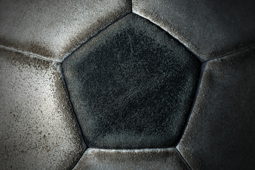 Macro photo of an old black and white soccer ball with pentagons and hexagons in leather