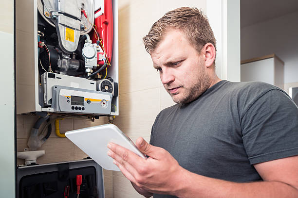 istock Repairman works on furnace using tablet 533357800