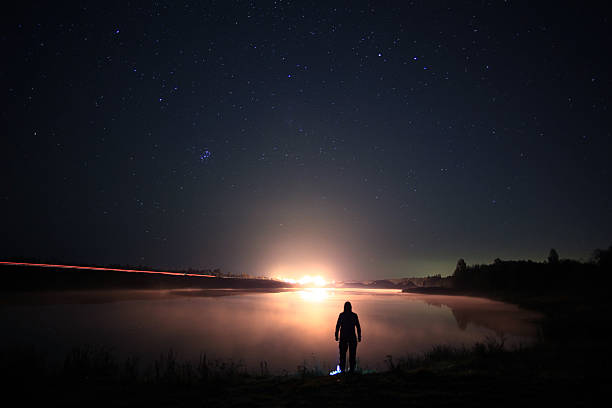istock night man at Lake starry sky space alien 533364313