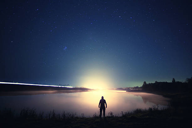 istock night man at Lake starry sky space alien 533364321