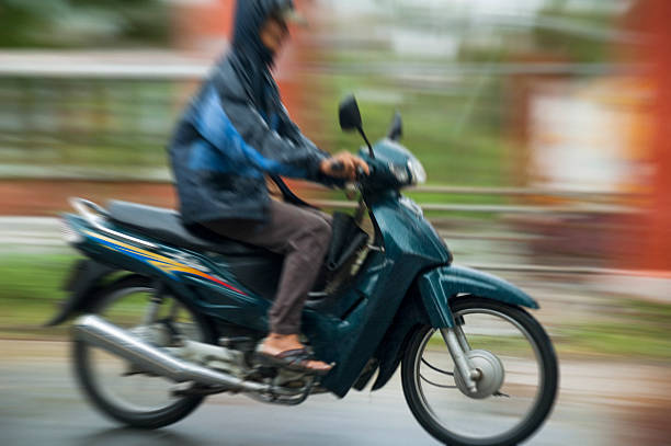 Hoi An, Vietnam - December 2, 2006: A man riding a motorcycle through heavy rain in Hoi An. Motorcycles are a common form of transport in Vietnam and are ridden in all kinds of weather