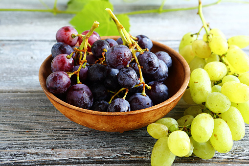 Bunches of grapes in bowl on wooden boards, sweet food