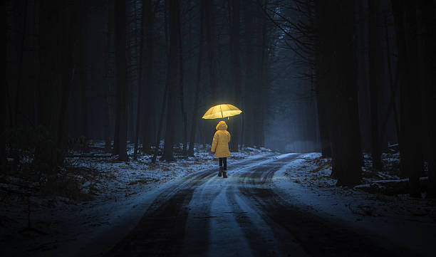 Little girl in the dark forest Little girl in the yellow coat with umbrella in the dark forest at night. Homage to Little Red Riding Hood dark road stock pictures, royalty-free photos & images