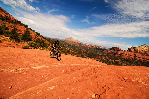 Panoramic view of mountain biker in desert Male mountain biker going uphill on slickrock trails in desert slickrock trail stock pictures, royalty-free photos & images
