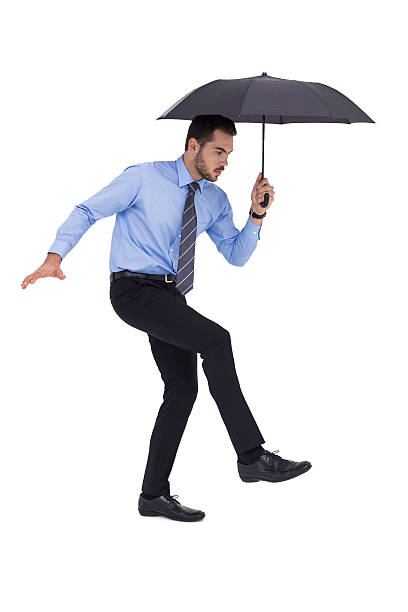 istock Focused businessman holding umbrella and balancing 533397235