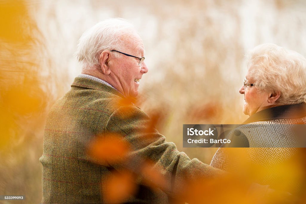 Senior couple sitting on a park bench A happy senior couple embracing outdoors. They are still in love after many years together. 2015 Stock Photo