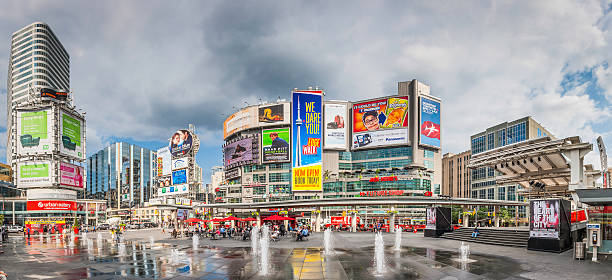 Toronto Yonge Dundas Square crowds fountains colourful billboards panorama Canada People relaxing, shopping and strolling in the central downtown plaza of Yonge-Dundas Square beside the Eaton Centre shopping mall and overlooked by the colorful billboards, movie posters and large advertising hoardings that cover the surrounding buildings, Toronto, Canada. ProPhoto RGB profile for maximum color fidelity and gamut. theatre building stock pictures, royalty-free photos & images