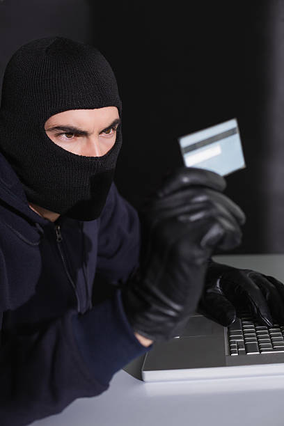 istock Hacker in balaclava spending money online 533419141