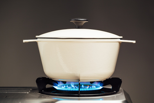 white cast iron saucepan on the gas stove with blue flame