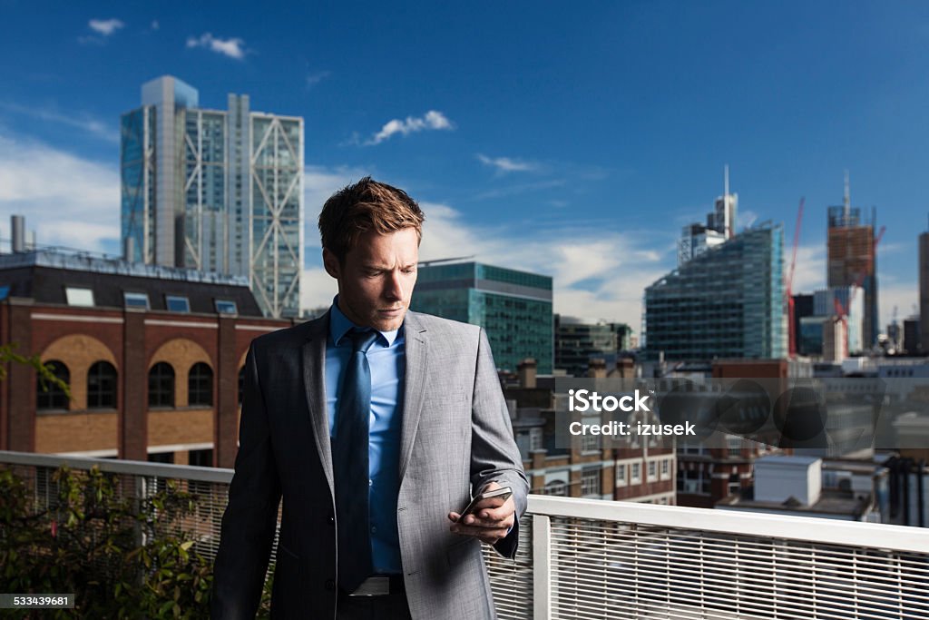 Outdoor portrait of businessman using smart phone Outdoor portrait of professional businessman using a smart phone with city scape in the background. 2015 Stock Photo