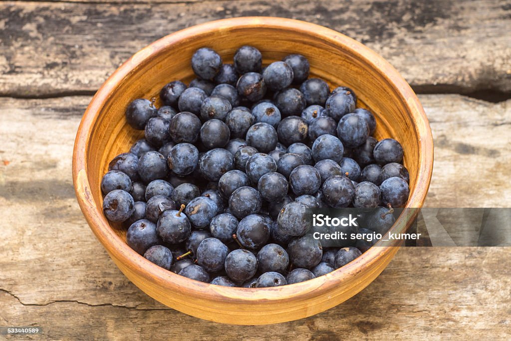 Ripe blackthorn berries in clay bowl on wood background 2015 Stock Photo