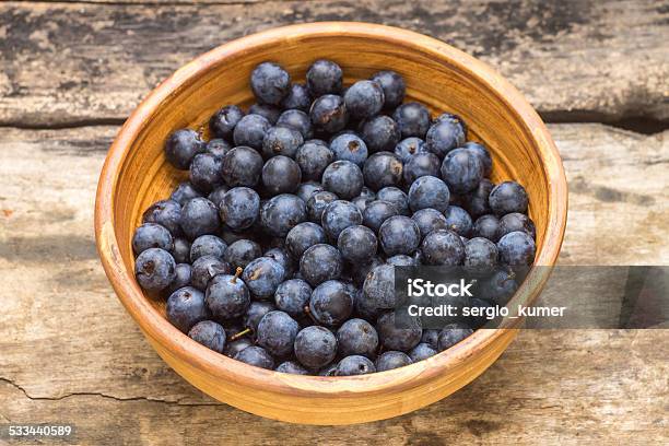 Ripe Blackthorn Berries In Clay Bowl On Wood Background Stock Photo - Download Image Now