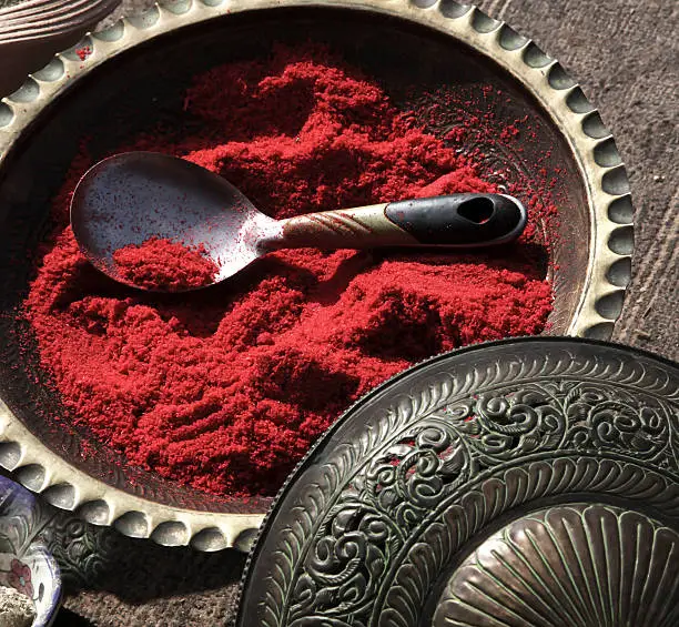 Red sumac spice in a middle eastern metal antique bowl, taken in the city of Petra in Jordan.  Sumac is a popular spice in the middle eastern cuisine.  Enhances the flavor of various recipes.  Usage of ornate metal work is common in every day dishes in the middle east.  Taken in the ancient city of Petra, a Bedouin was selling  the spice sumac on a hiking trail to the monastery.
