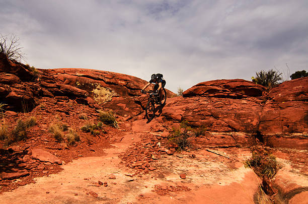 Mountain biking on the rocks Male mountain biker going down on steep rocks in desert slickrock trail stock pictures, royalty-free photos & images