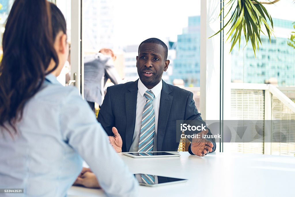 Job interview Young woman having job interview in an office, focus on afro american businessman. City scape in the background. African-American Ethnicity Stock Photo