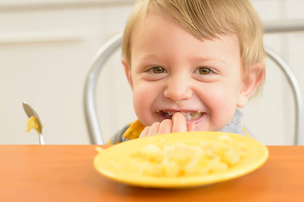 Cute little boy eating and smiling in the kitchen