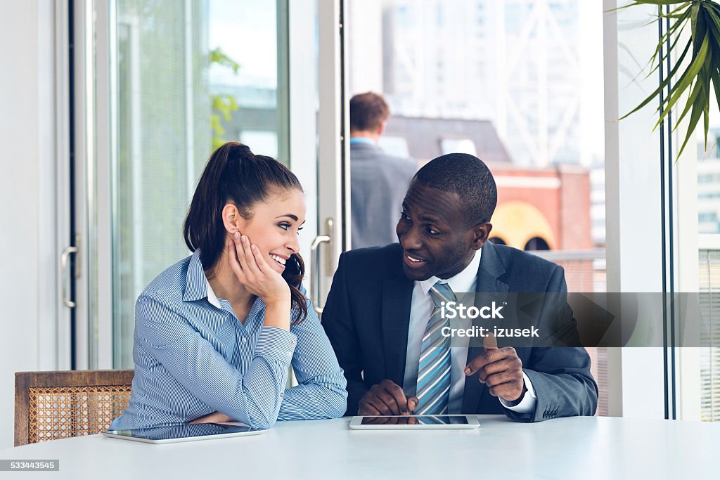 Business people discussing project on digital tablet Afro american businessman discussing project on digital tablet with his female business partner. 2015 Stock Photo