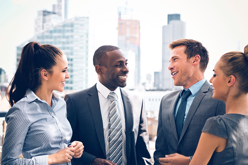 Group of happy business people talking outdoor with city scape in the background.