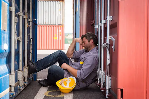 Photo of adult worker in large container port, sleeping