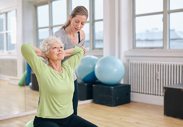 istock Trainer helping senior woman exercising 533445331