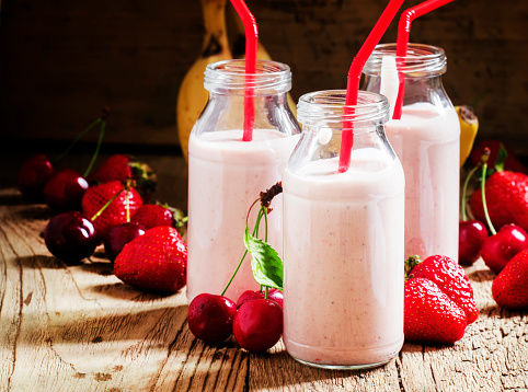 Strawberry Banana smoothie with cherry in glass bottles