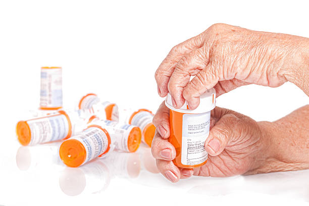 Senior adult , arthritic hands opening a pill bottle stock photo