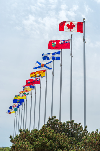 Windsor, Ontario, Canada - September 13, 2022:  The Canadian flag flying at half-mast overlooking the downtown Windsor skyline.
