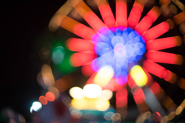 遊園地の観覧車光がぼやけた夜の背景 - ferris wheel wheel blurred motion amusement park ストックフォトと画像