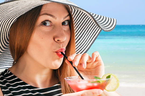 istock young woman in sunhat drinks cocktial 533453478