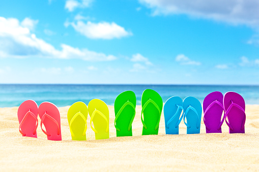 Spring break vacation party on a tropical beach. Rows of flip-flops partying on beach.