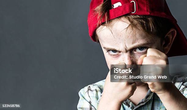 Threatening Boy With Freckles And Red Hat Back Looking Violent Stock Photo - Download Image Now